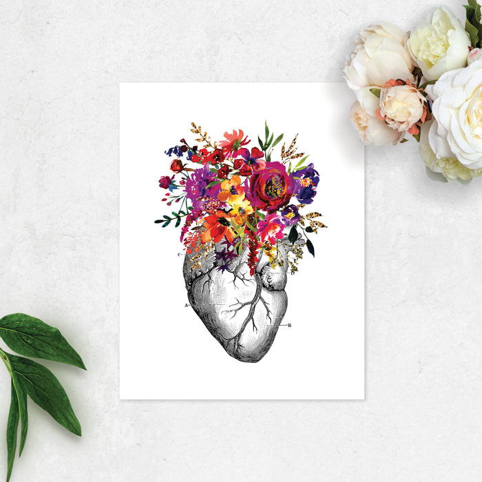 vintage etching of an anatomical heart topped with watercolor flowers in shades of pink, purple, yellow, and golden tones printed on matte white paper