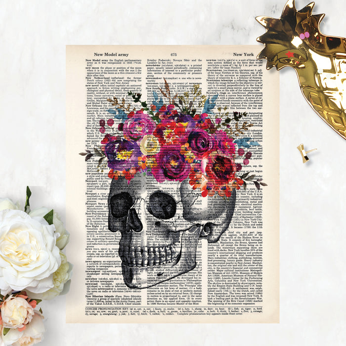 skull etching topped with pinke, yellow, purple, and blue watercolor flowers printed on a dictionary page