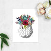 vintage etching of the top view of a brain topped with watercolor flowers in shades of blues and reds on matte white paper