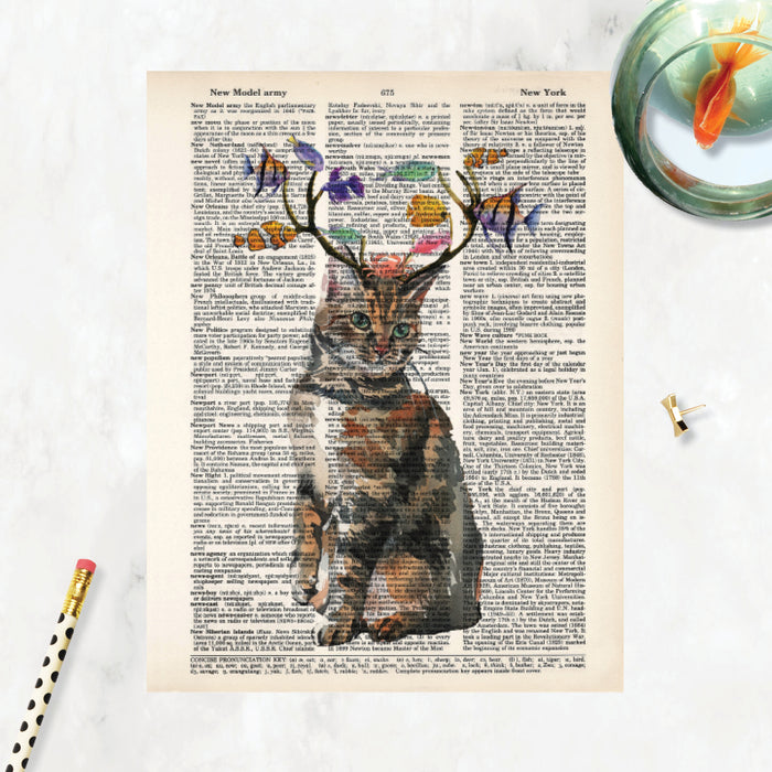 cat with antlers and fish nibbling on the antlers with a crab on the cats head, all in watercolor printed on dictionary page