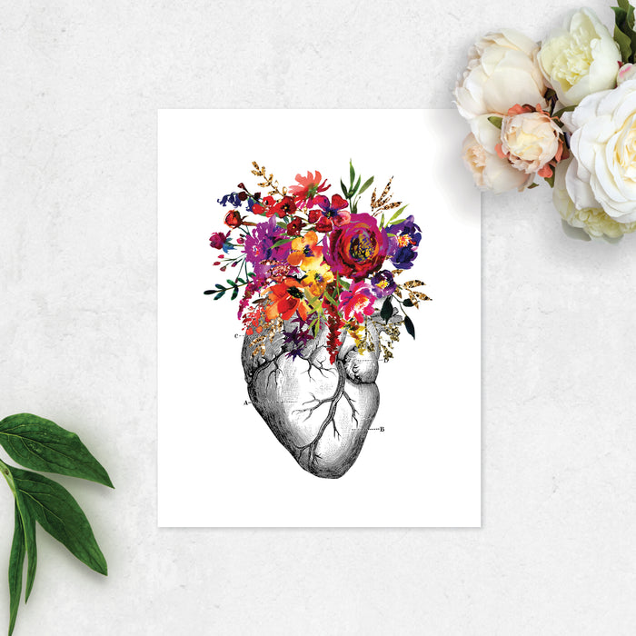 vintage etching of an anatomical heart topped with watercolor flowers in shades of pink, purple, yellow, and golden tones printed on matte white paper