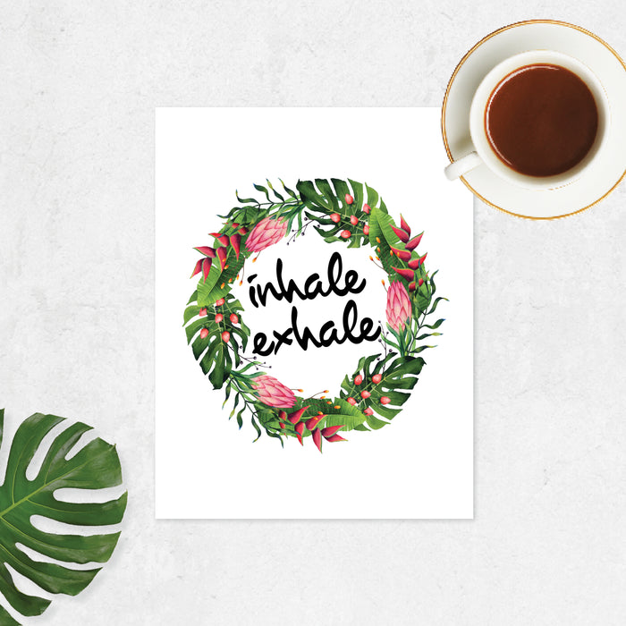 watercolor tropical leaves and flowers in a wreath shape with the words inhale exhale in black in printed on matte white paper