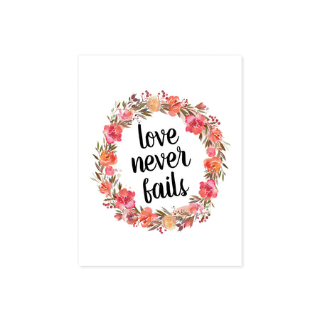 love never fails surrounded by a wreath of pink and coral watercolor flowers with greenery printed on matte white paper