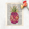 shades of pink watercolor tropical flowers form the shape of a pineapple with traditional pineapple greenery at the top printed on a dictionary page