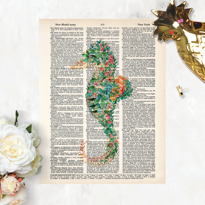 seahorse made of tropical flowers and greenery with coral and pink and blue tones printed on a dictionary page